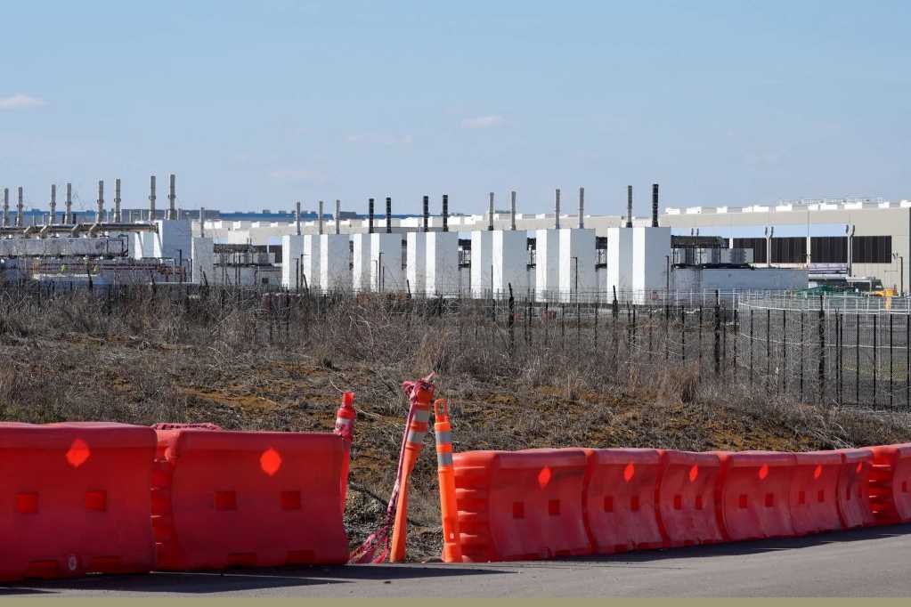Rows of generators stand beside a large building