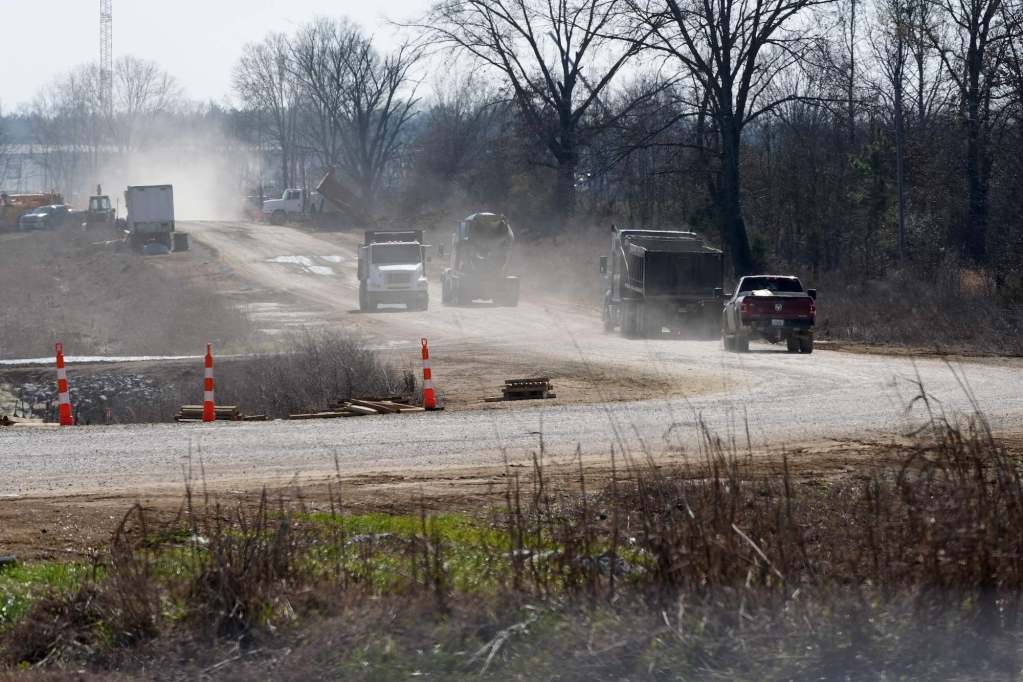 Large trucks drive two and from a construction site