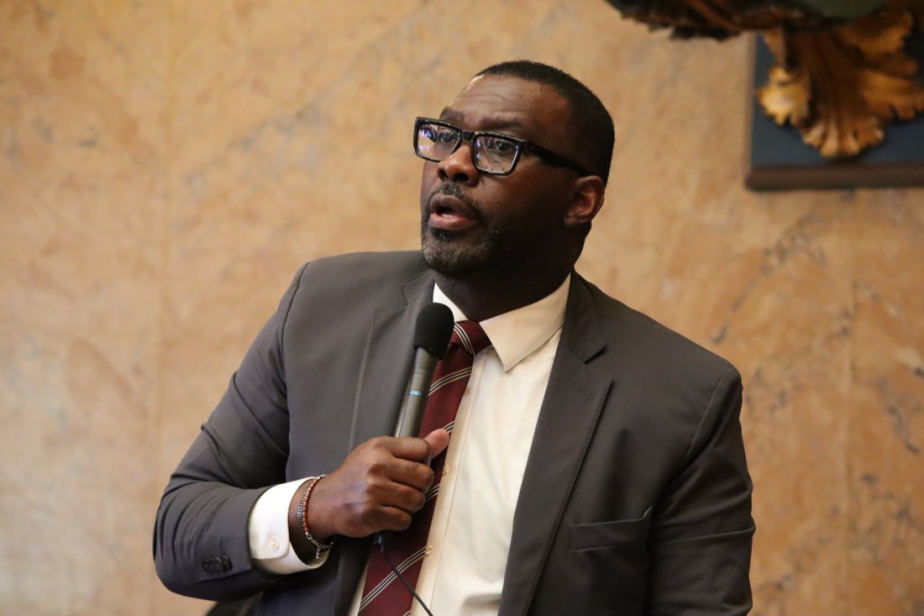 Bryant Clark, in a grey suit, speaks in the senate