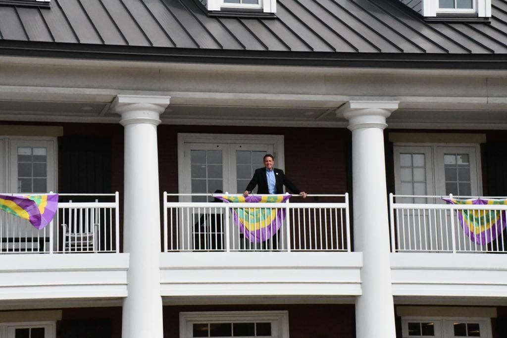 A man standing on the balcony of a two-story building. 