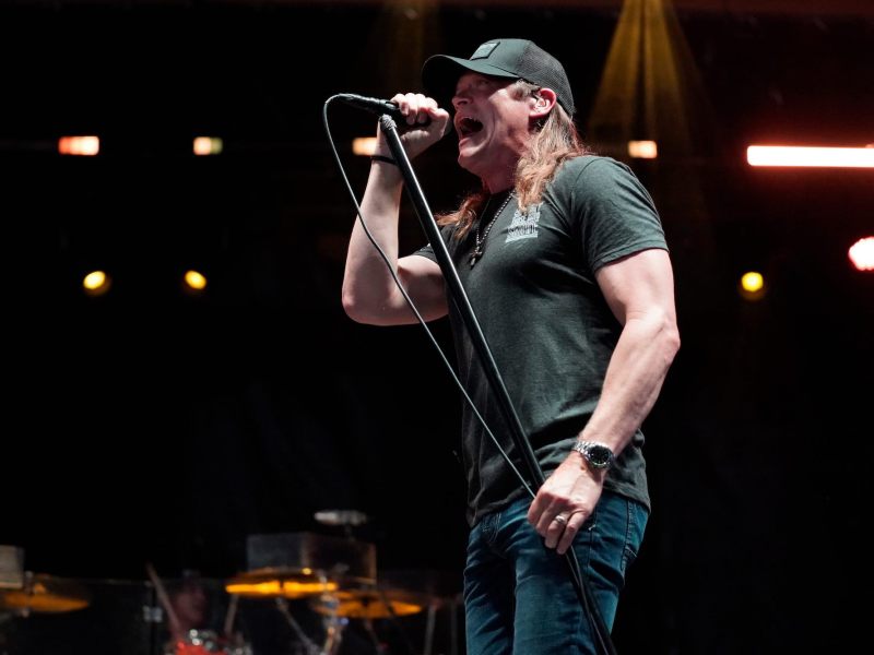 A man wearing a baseball cap singing into a microphone.