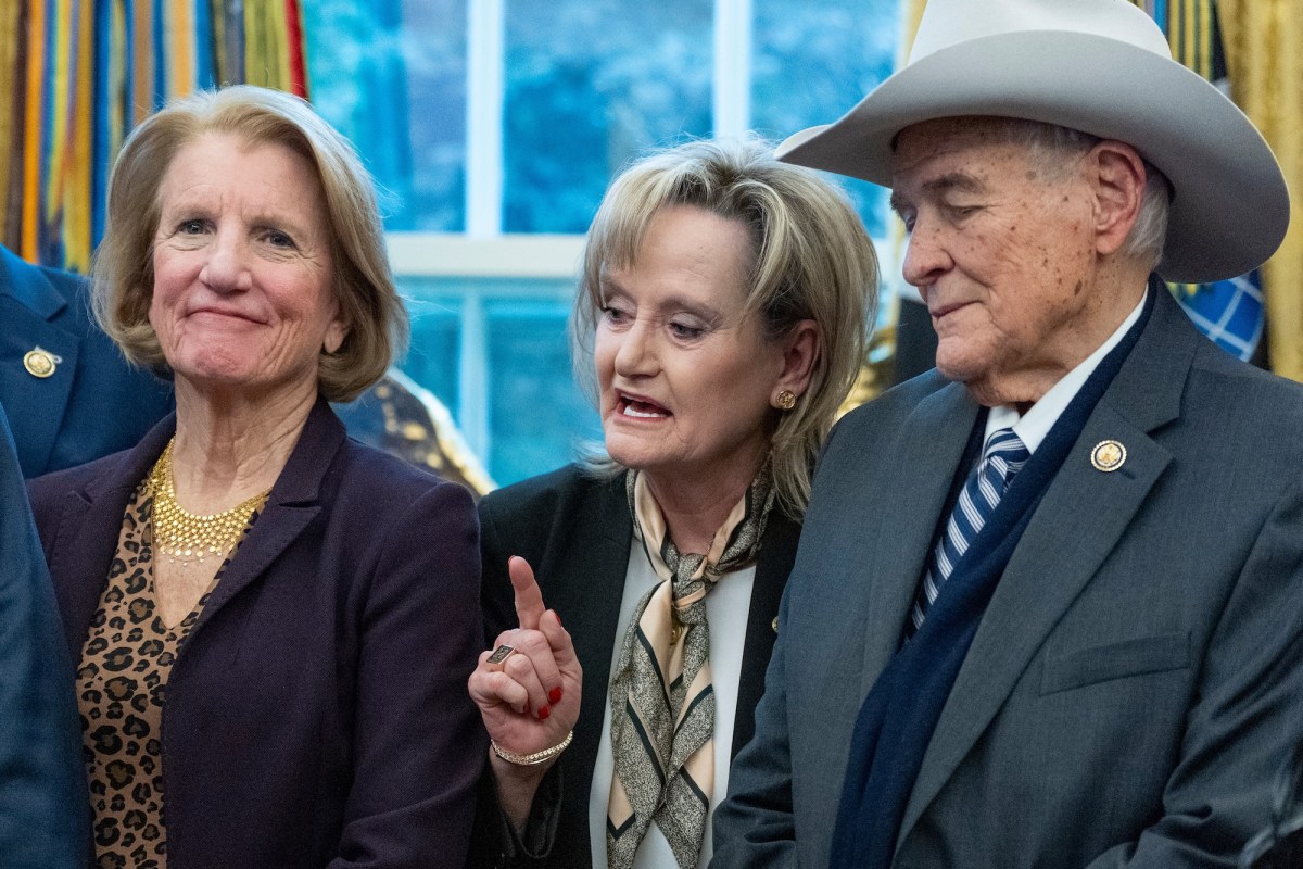 a photo of a woman holding a finger up and speaking in the center surrounded by another woman who is smiling and a man in a cowoby hat