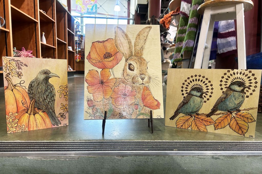 Three pieces of wood-burned art with color added featuring animal motifs