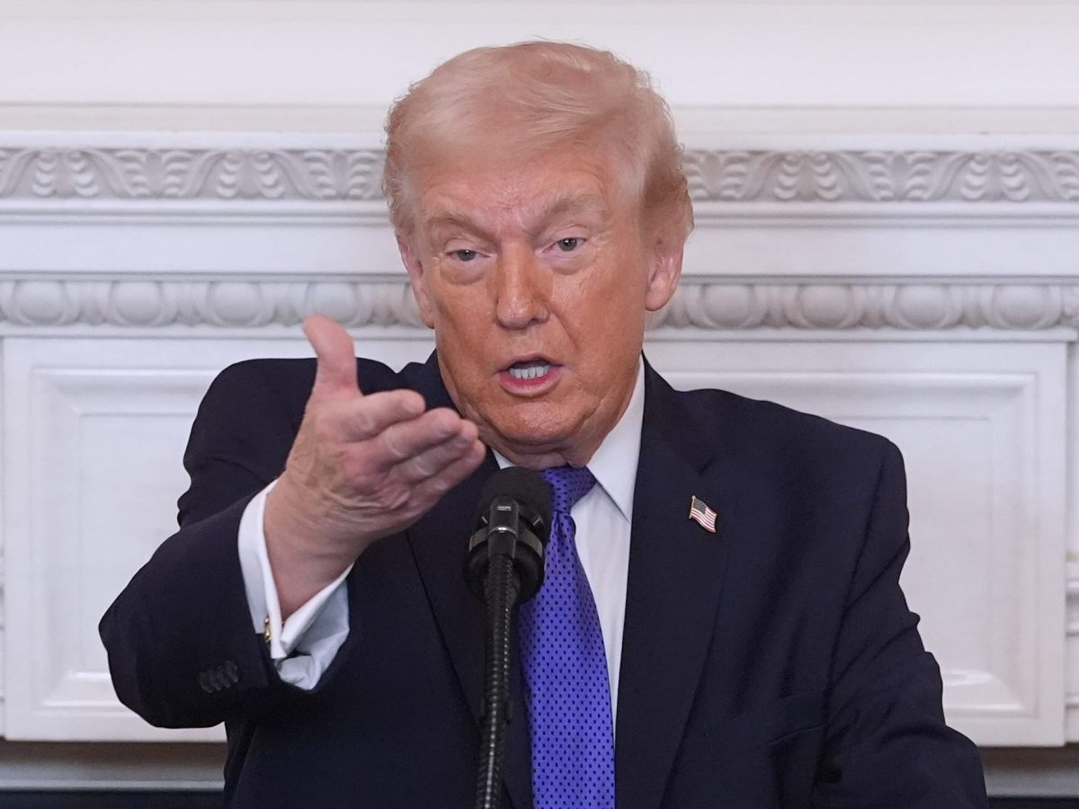 Donald Trump speaking into a microphone and gesturing with his right hand