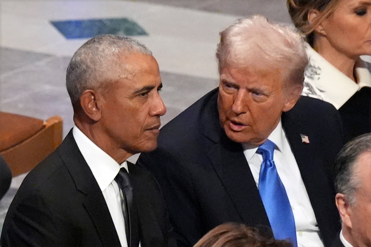 President Trump whispers into President Obama’s ear while seated next to him