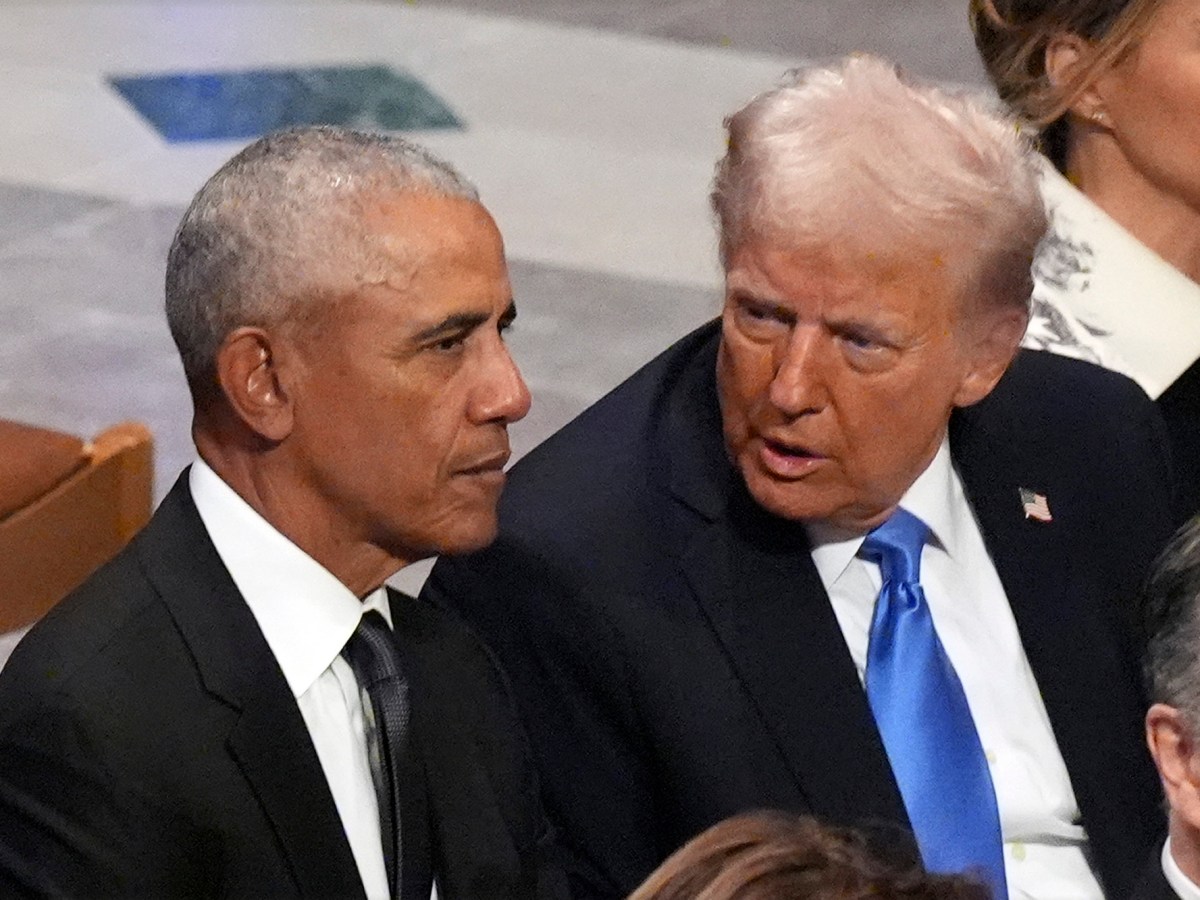 President Trump whispers into President Obama’s ear while seated next to him