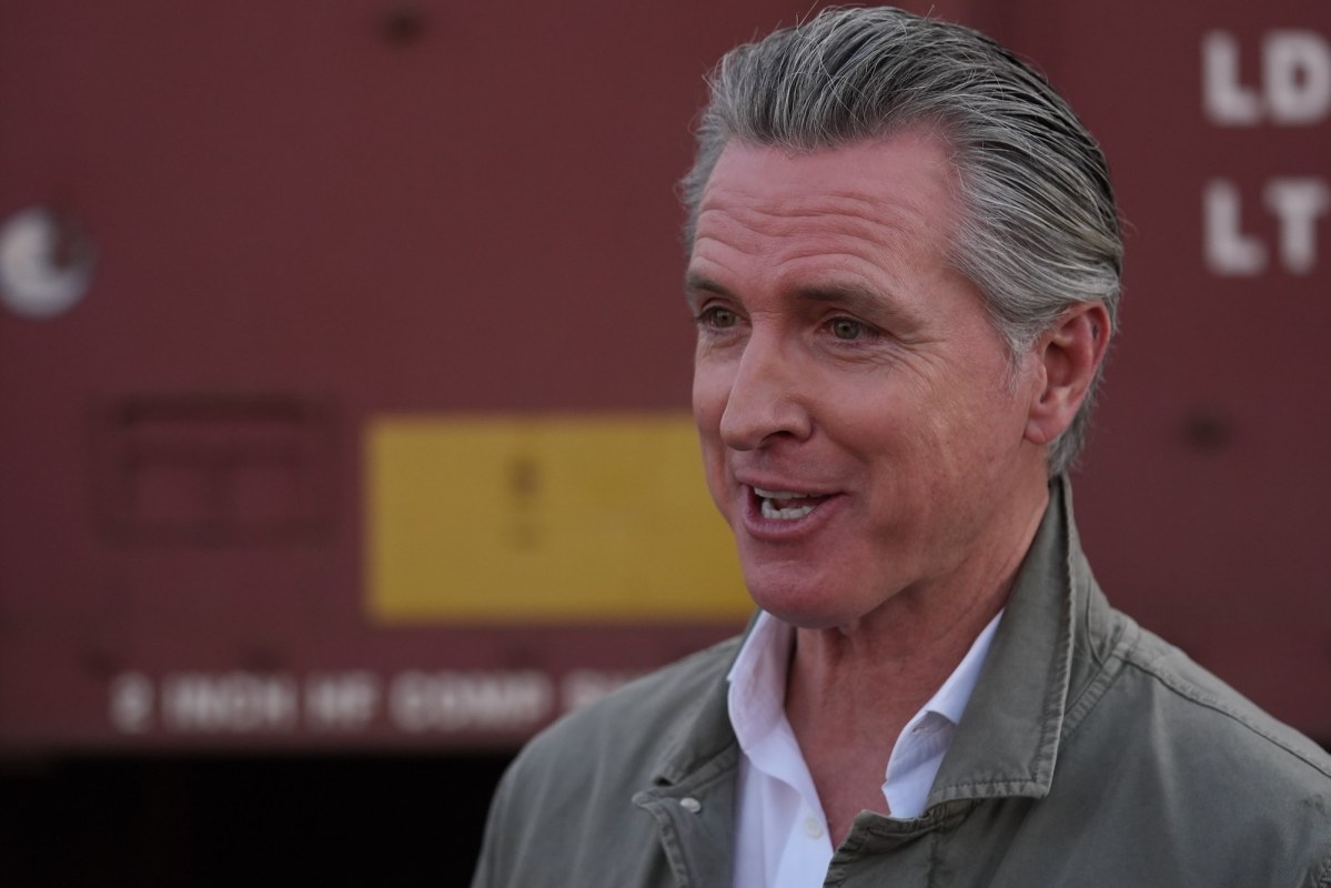 Gavin Newsom speaking with a red train car in the background.