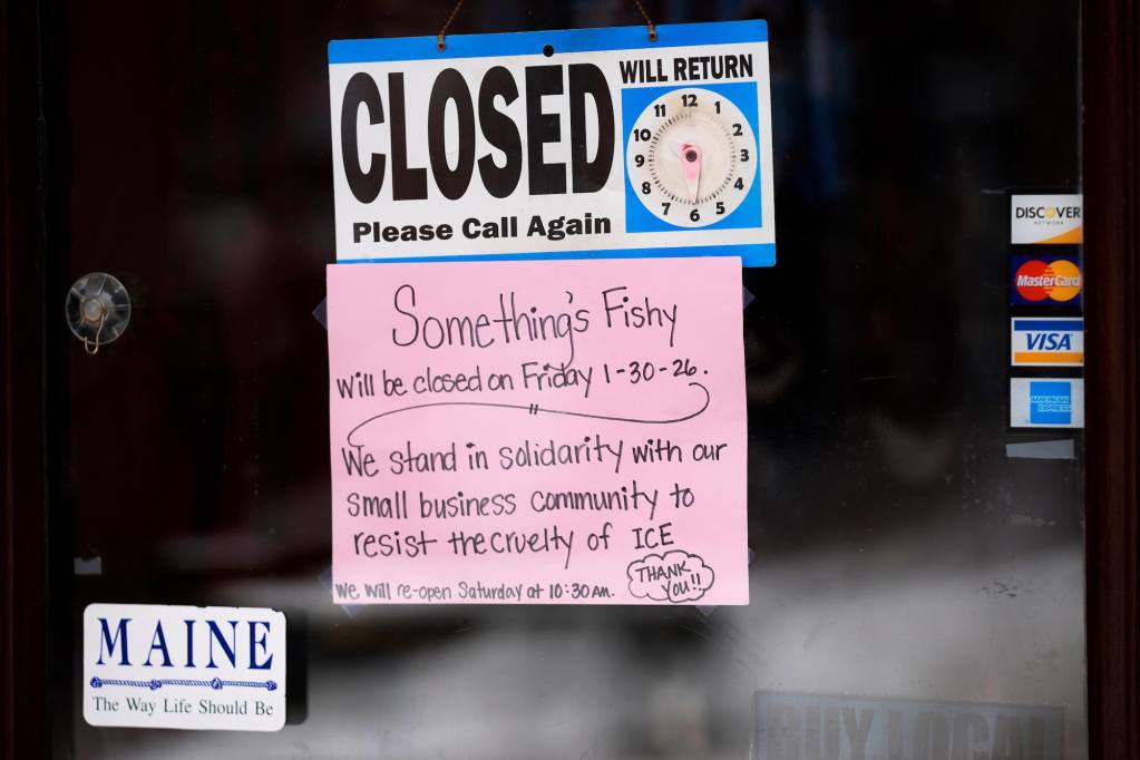 A closed sign on a door and beneath it a pink paper sign that reads, “Something’s Fishy will be closed on Friday 1-30-26. We stand in solidarity with our small business community to resist the cruelty of ICE.”
