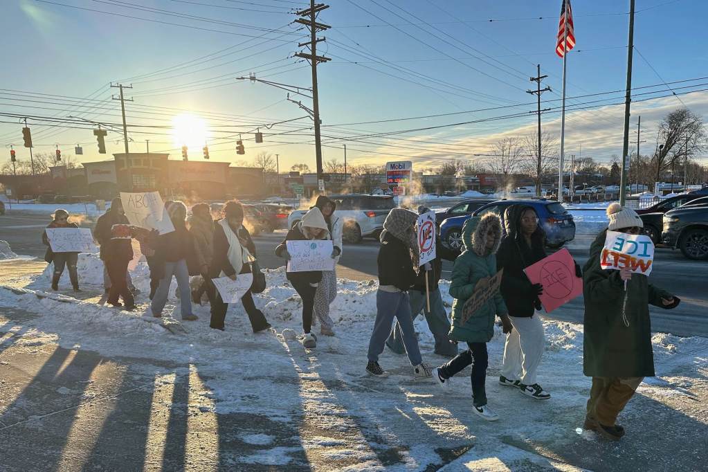 A line of high school students at a protest walking on snowy ground.