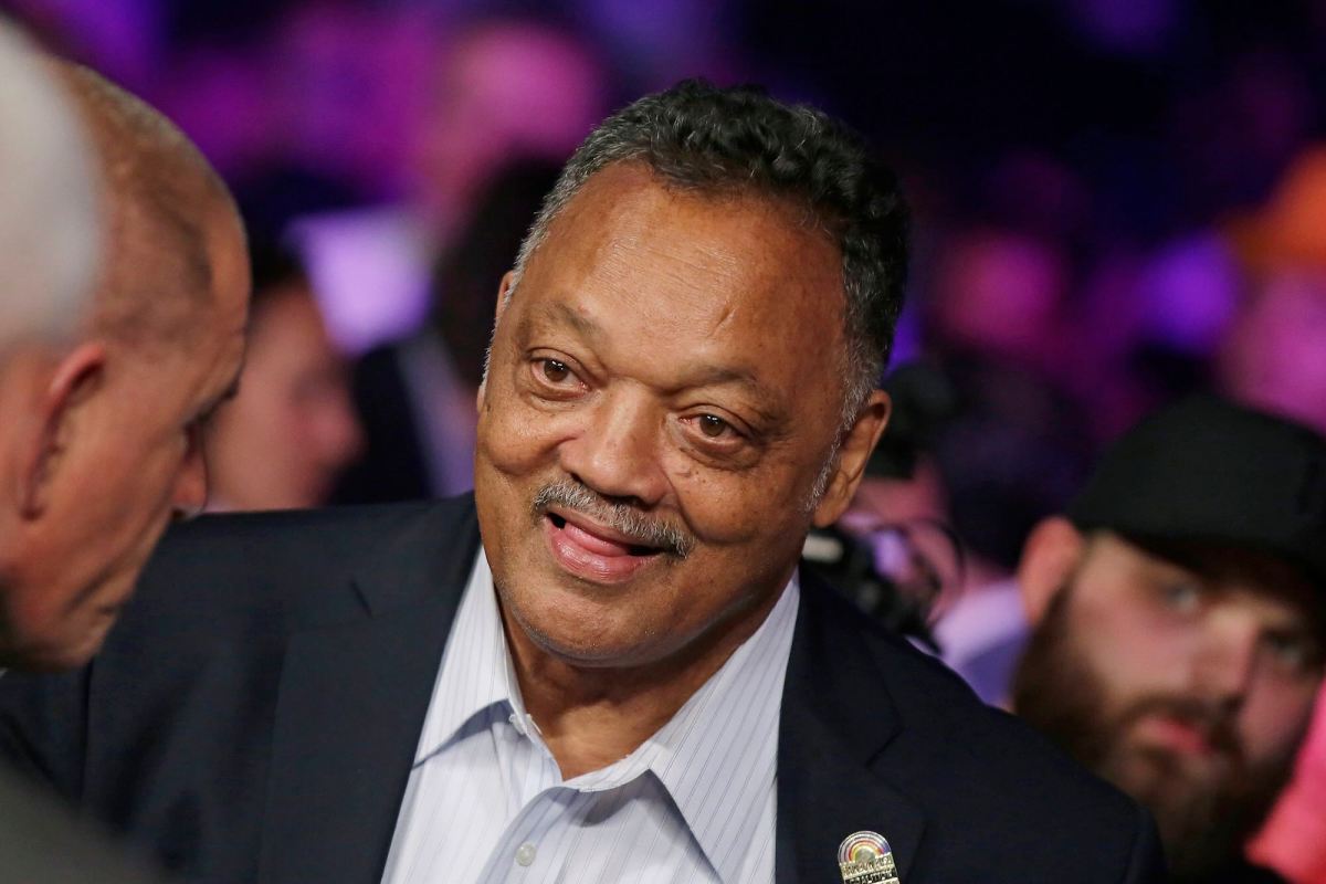 Jesse Jackson standing to greet someone in a crowd