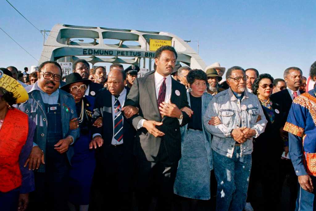 Jesse Jackson is among the first in a massive crowd walking across the Edmund Pettus Bridge