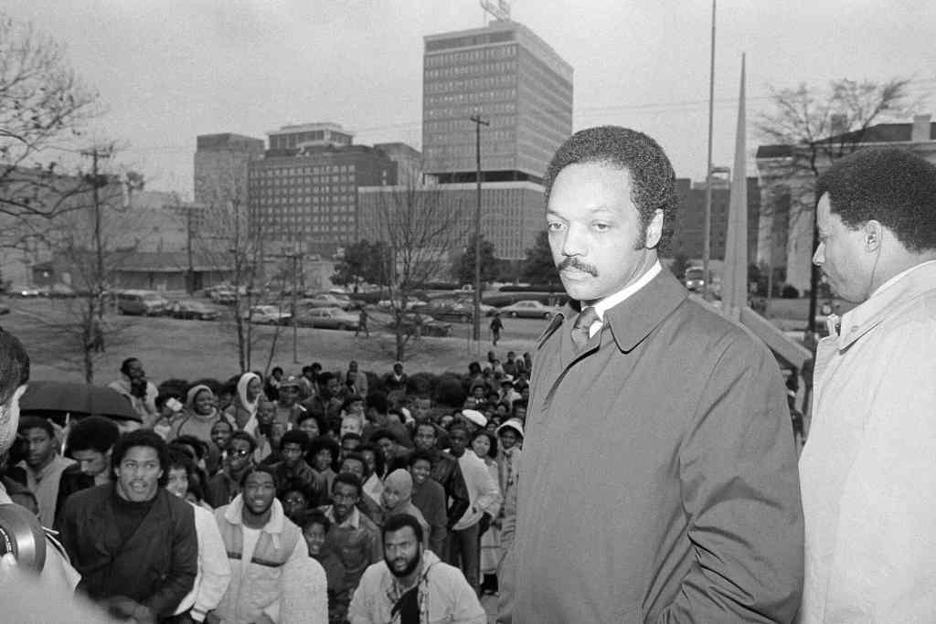 An old black and white photo of Jesse Jackson in downtown Jackson, MS with a crowd of people outside a courthouse
