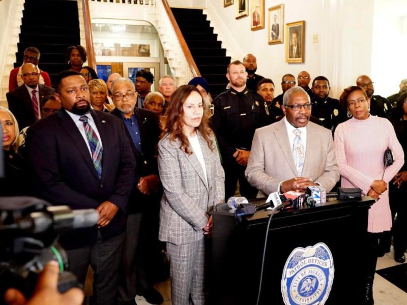 A group of people organized in rows behind a podium at a press conference