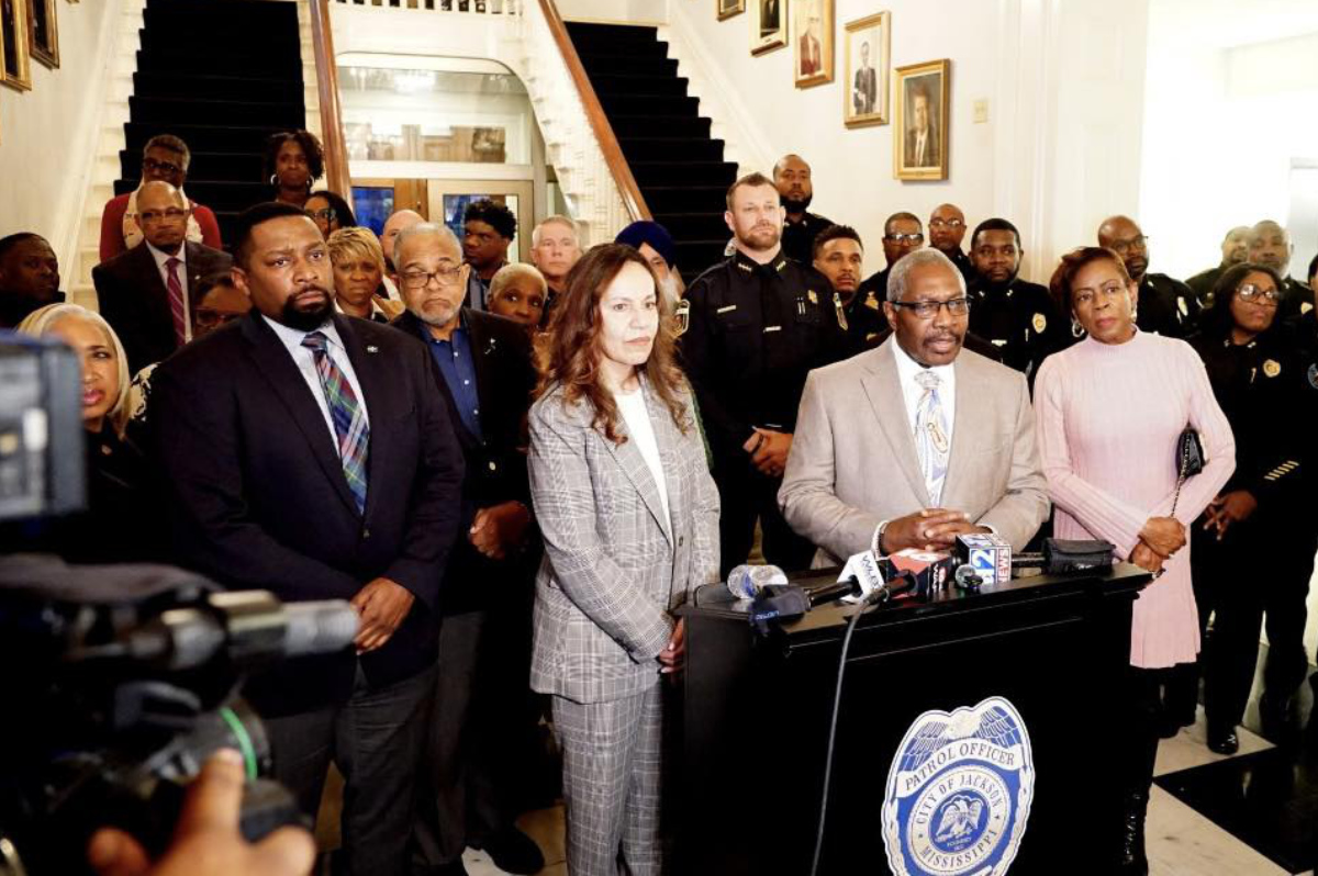 A group of people organized in rows behind a podium at a press conference