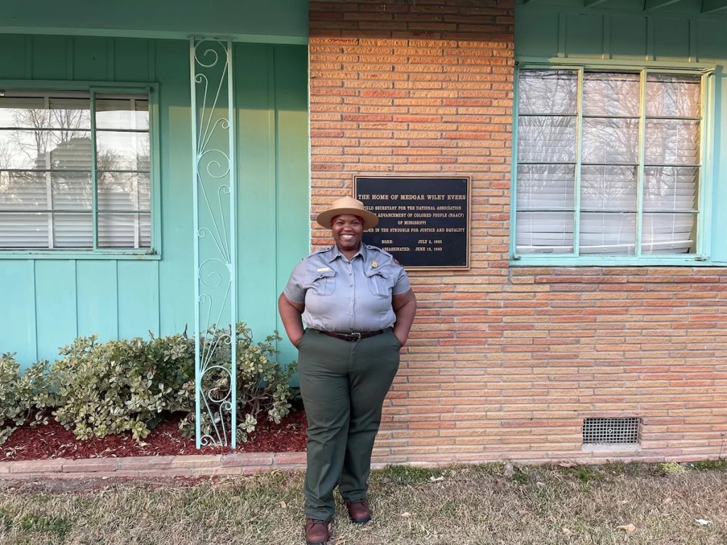 a woman wearing a national park service uniform stands outside the Medgar and Myrlie Evers home