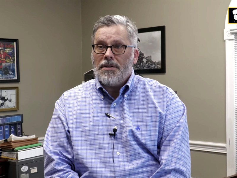 Layne Bruce speaking from inside his office