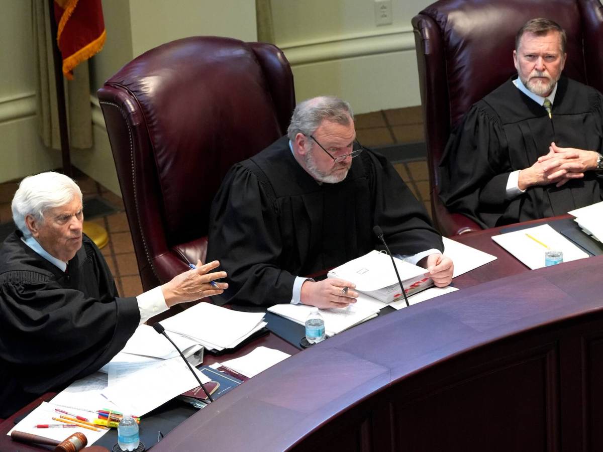 Three justices listening and speaking from their seats behind the bench