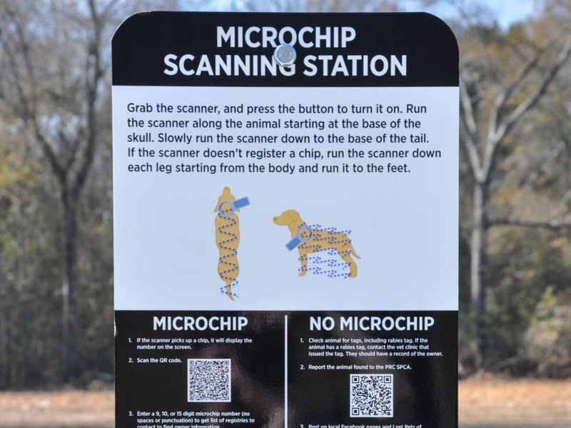 A microchip scanning station standing outside in a park, with instructions on how to scan pets for microchips