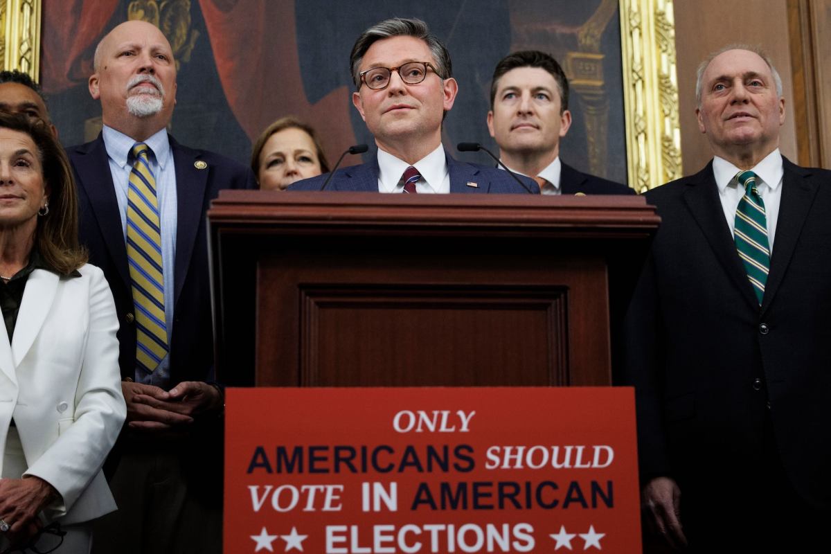 Mike Johnson and other political figures stand behind a podium labeled 'Only Americans Should Vote in American Elections'
