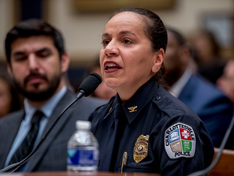 a woman in a Charlottesville Police uniform answers questions at a microphone
