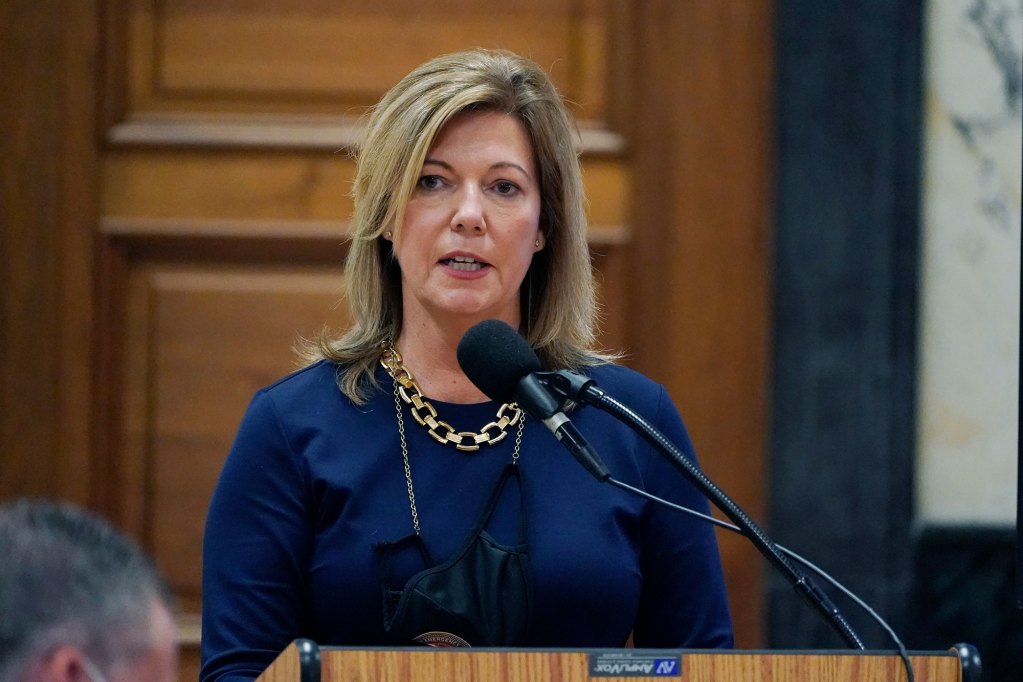 A woman in a blue outfit stands behind a podium