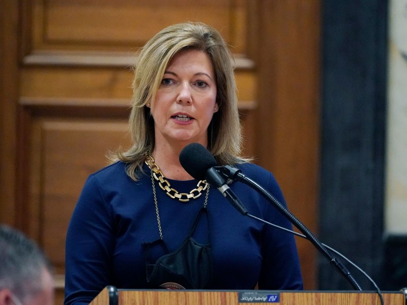A woman in a blue outfit stands behind a podium