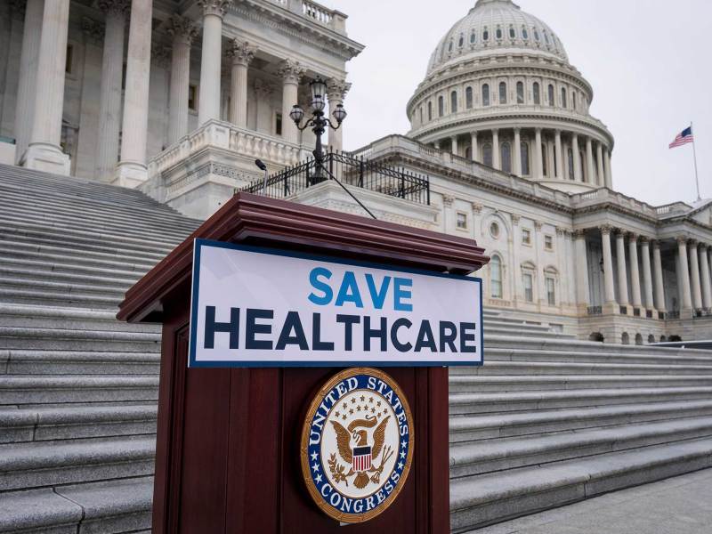 A wooden podium with a sign that says, “Save Healthcare.” The U.S. Capitol building is in the background.