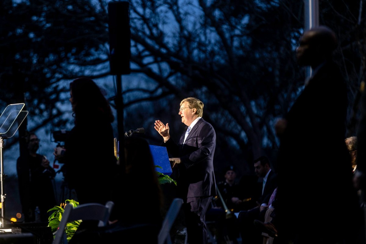 Gov. Tate Reeves speaks from an outside stage at night