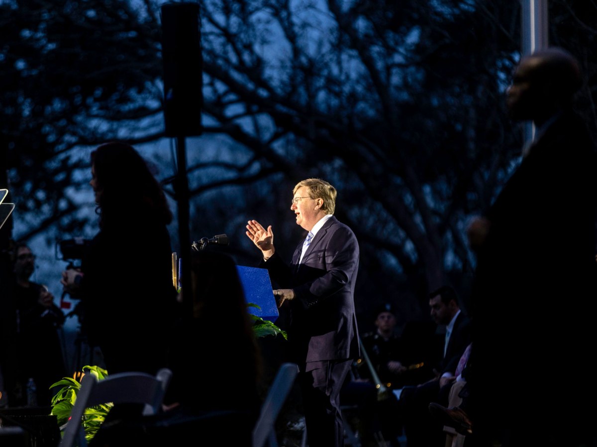 Gov. Tate Reeves speaks from an outside stage at night