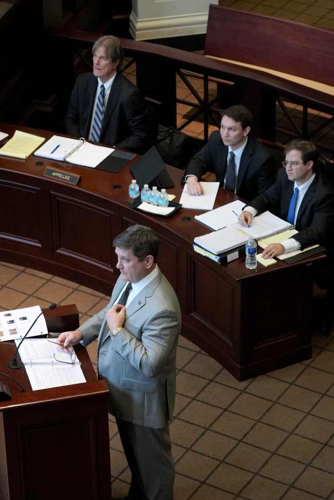 William Quin II, in a light grey suit, speaking at a podium