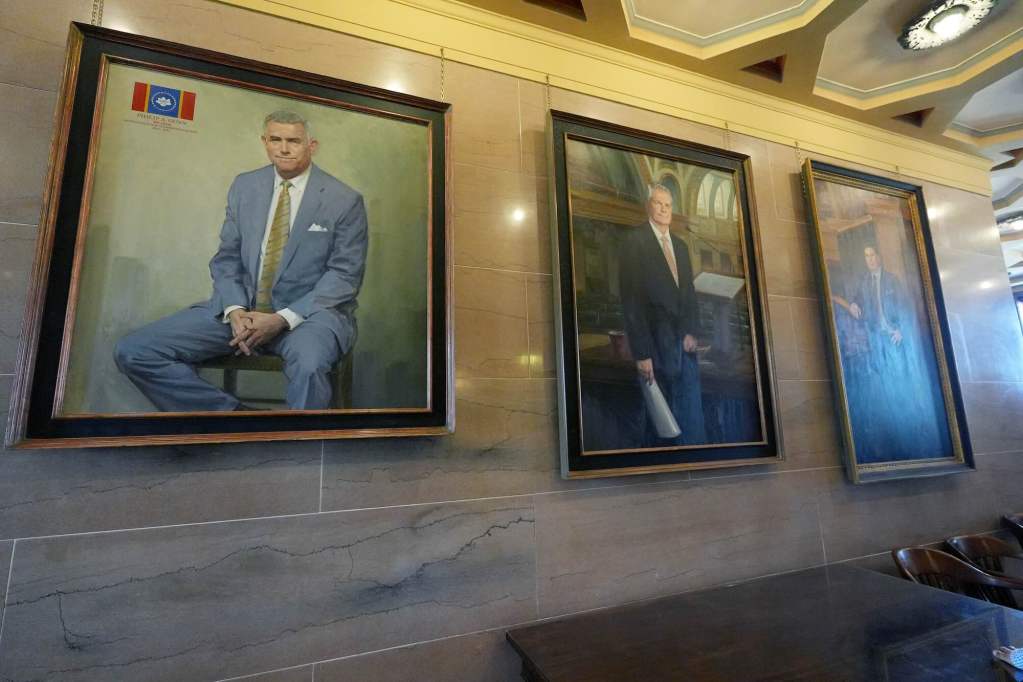 Three portraits hang on a marble wall, Philip Gunn's on the left