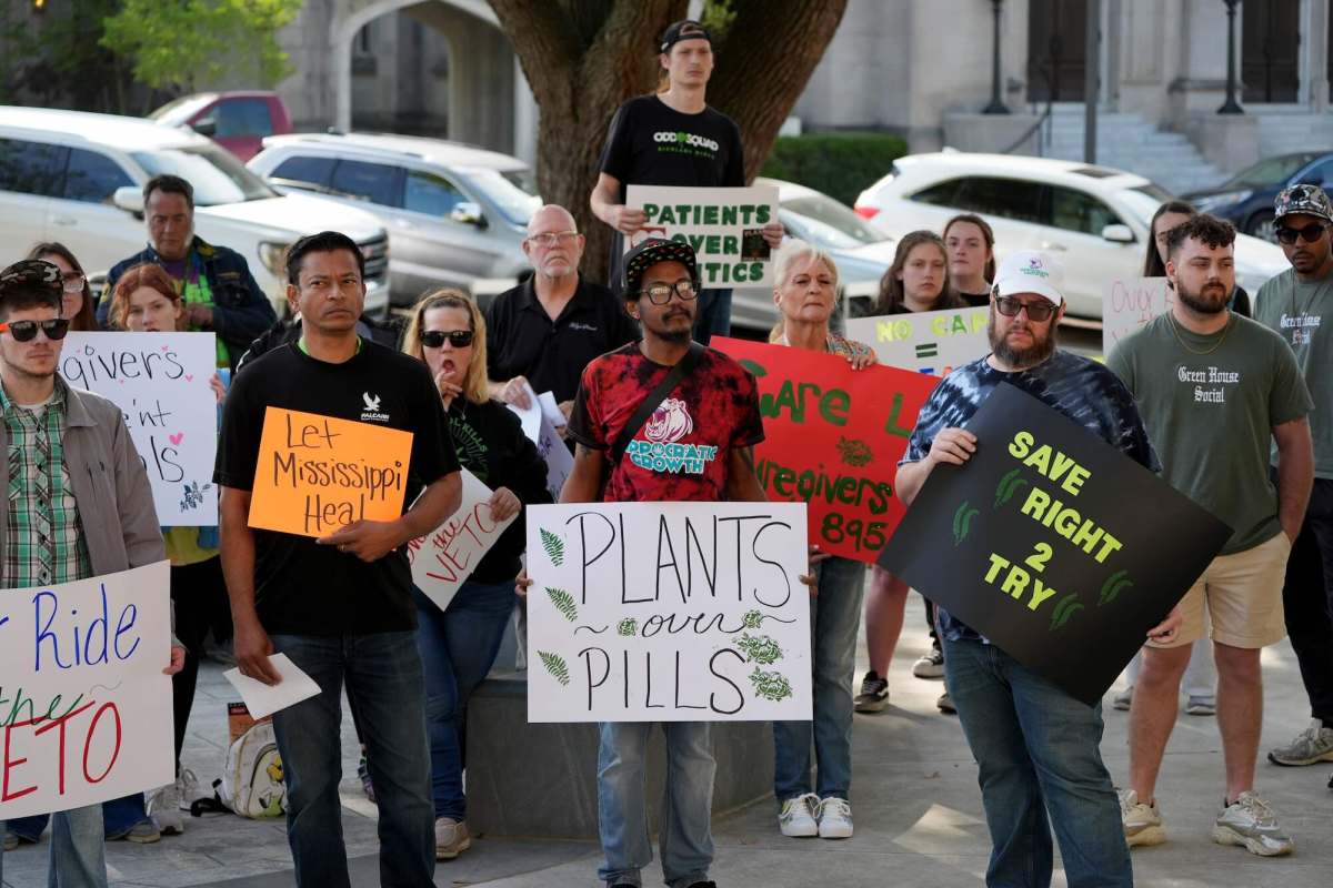A group of advocates gather outside with signs that reads 'Plants Over Pills' "Let Mississippi Heal'