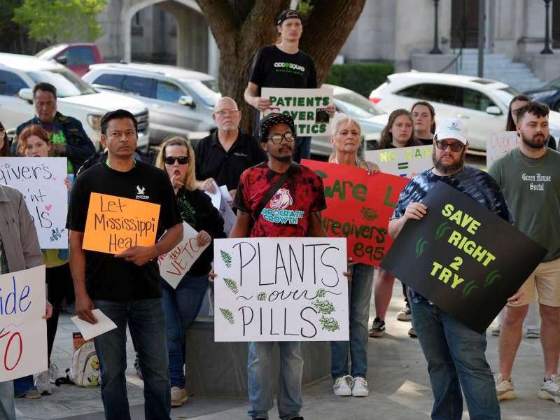 A group of advocates gather outside with signs that reads 'Plants Over Pills' "Let Mississippi Heal'
