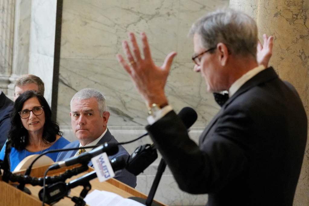 A man speaks at an event as others look on