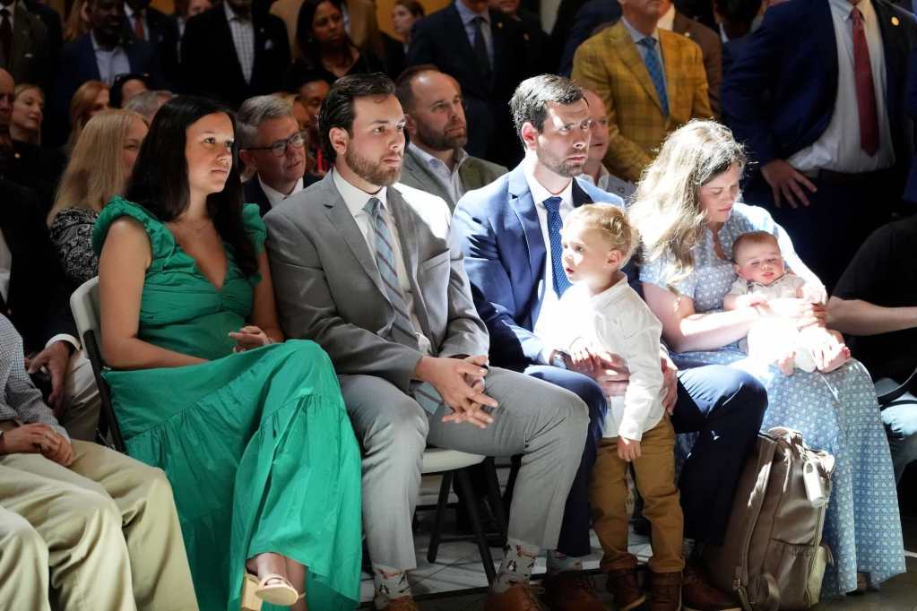 Family members seated at an event, the sun shining down on them from windows above