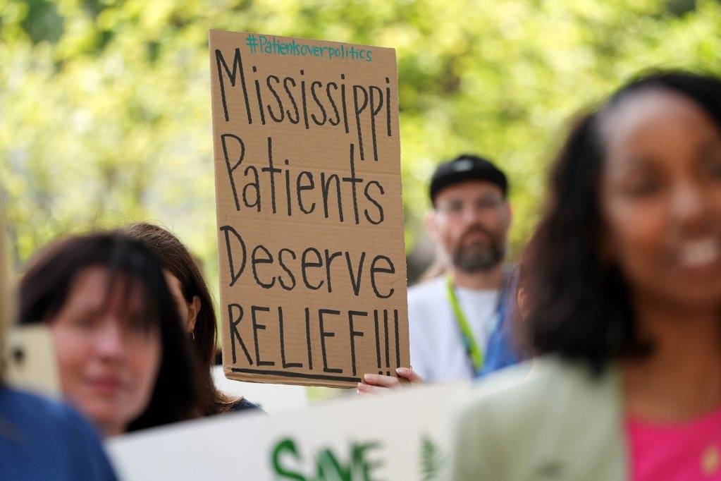 People hold signs, one reads 'Mississippi Patients Deserve Relief!'