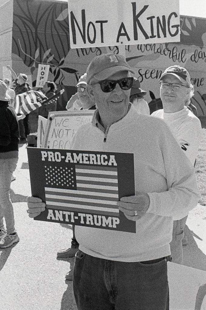 A man at a protest holds a sign that reads 'Pro-America Anti-Trump'