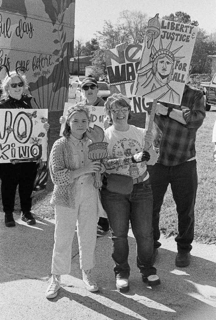 A group of protesters holding signs and Liberty torches