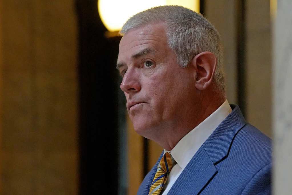 A closeup of Philip Gunn in a blue suit and gold striped tie, looking at the audience of an event