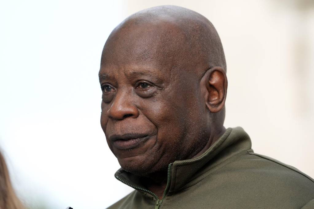 Closeup of a man in a green zip up sweater, speaking outside