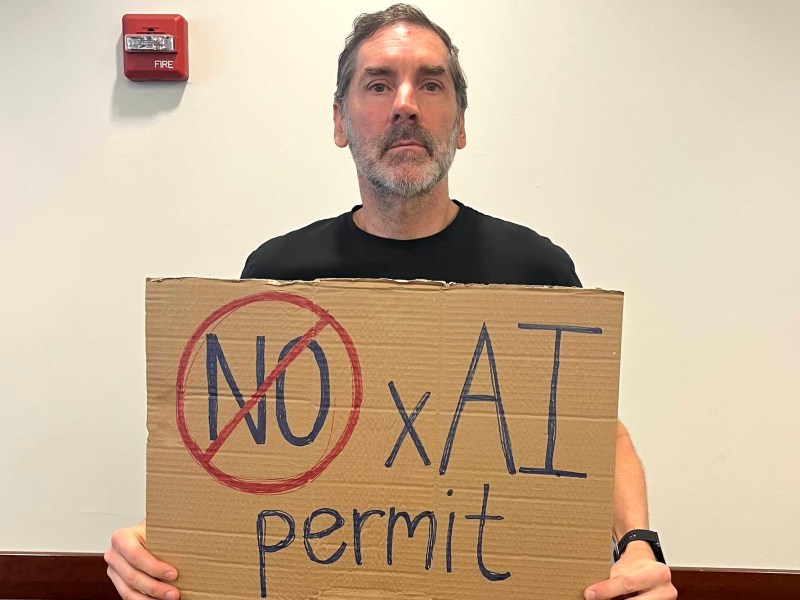 A man holding a sign that says No xAI permit
