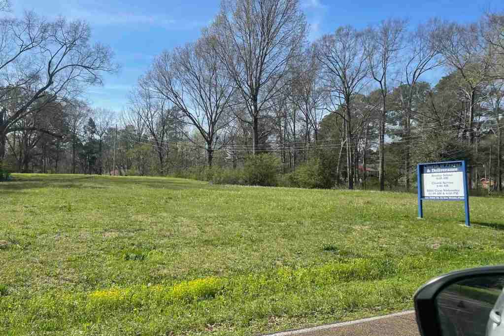 An empty green field with a sign Deliverance church