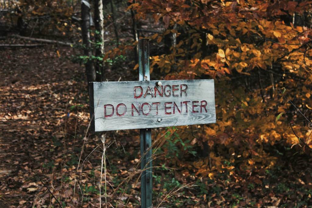 A sign that reads DANGER DO NOT ENTER in a wooded area