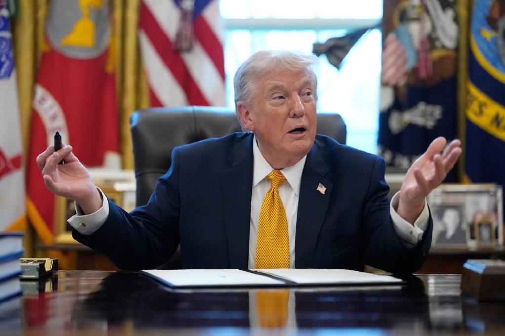 Donald Trump speaking while seated at a desk in the Oval Office