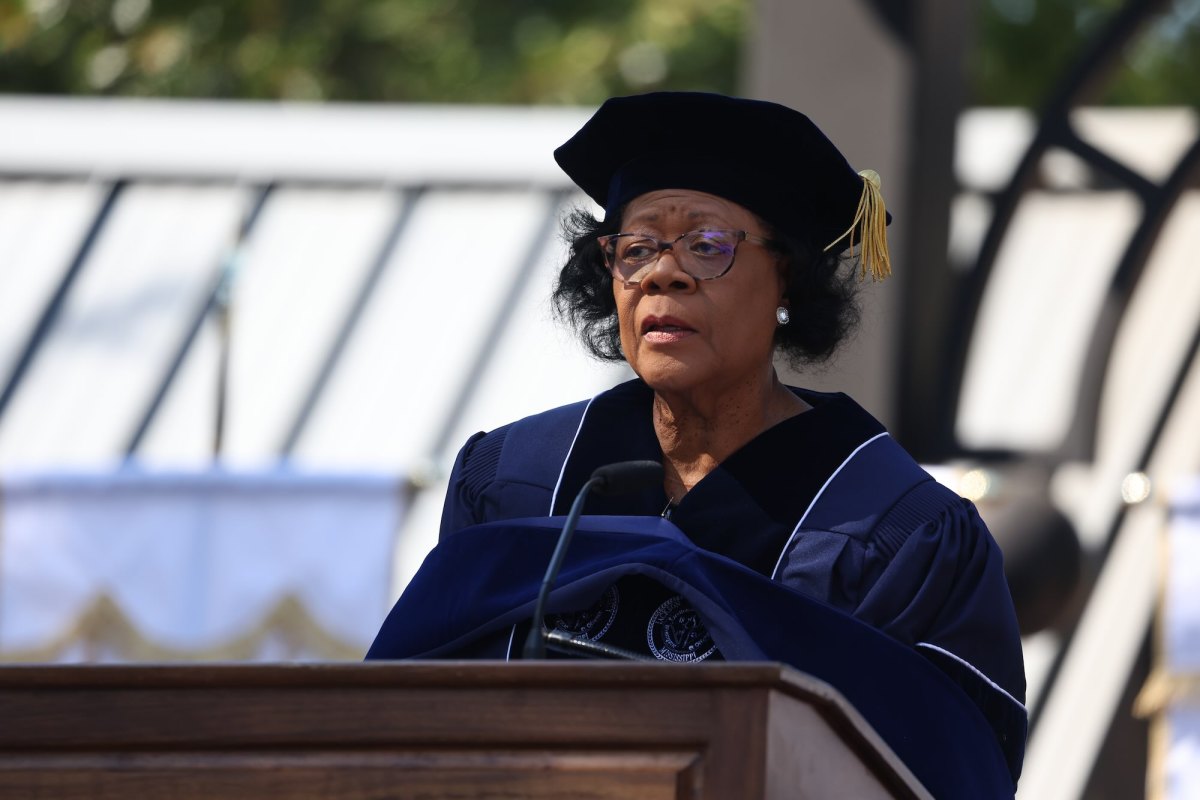 Elayne Hayes-Anthony in cap and gown speaking outside at a graduation event