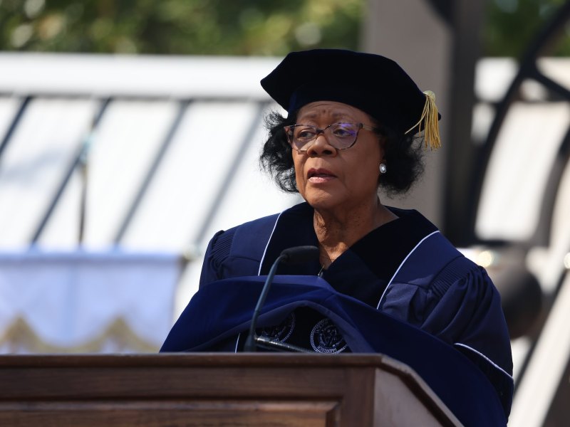 Elayne Hayes-Anthony in cap and gown speaking outside at a graduation event