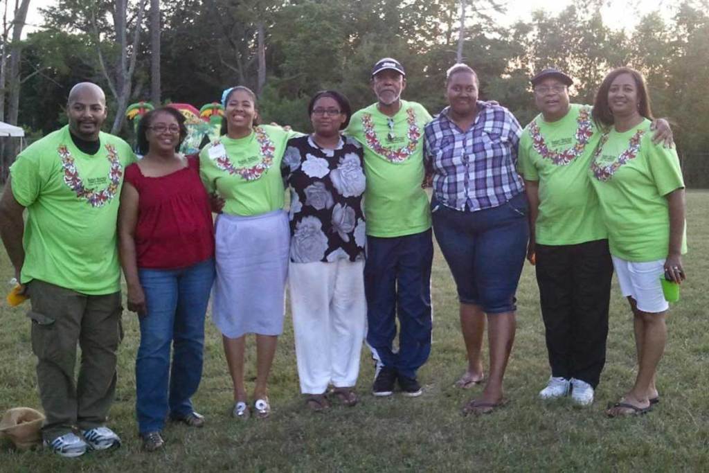 A group of people standing together in a line outside. Half of them are wearing matching bright green shirts