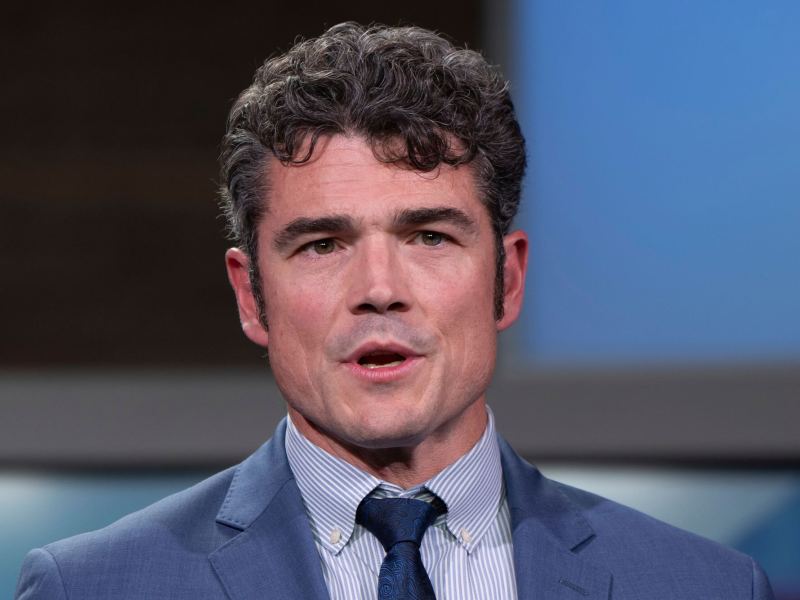A close up of a man in a blue suit, speaking