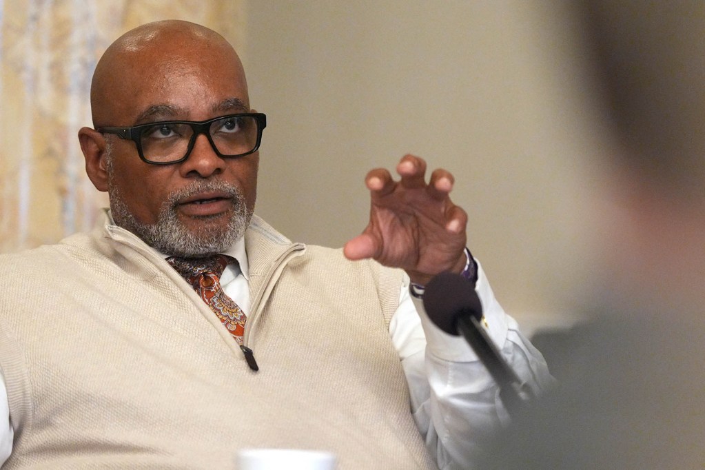 John Hines Sr. seen sitting in a meeting, speaking with one hand gesturing in the air