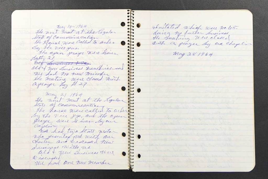 An open ledger filled with hand written notes in blue ink, a date reading 'May 28, 1964' visible at the end